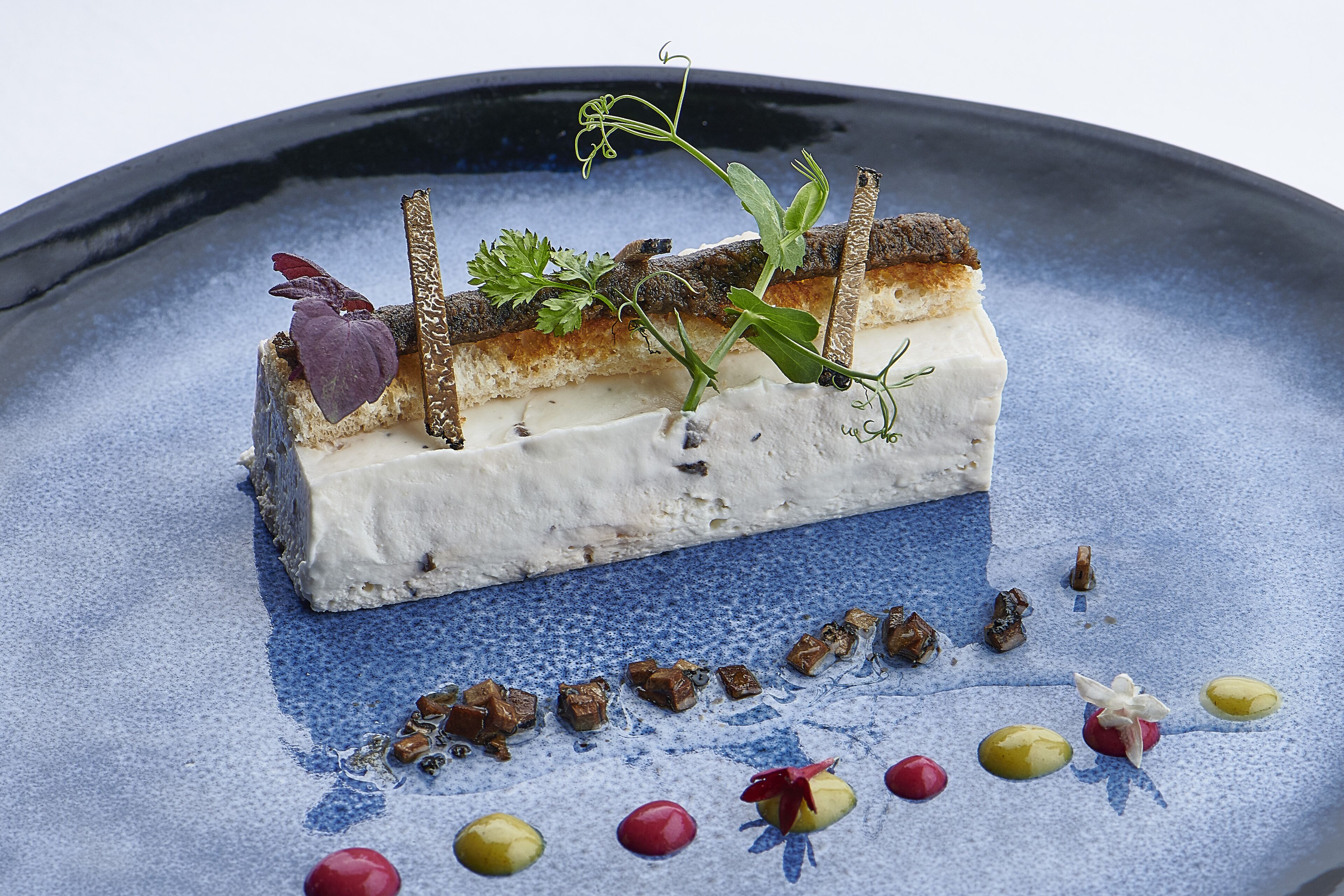 A dessert on a blue plate with various garnishes.