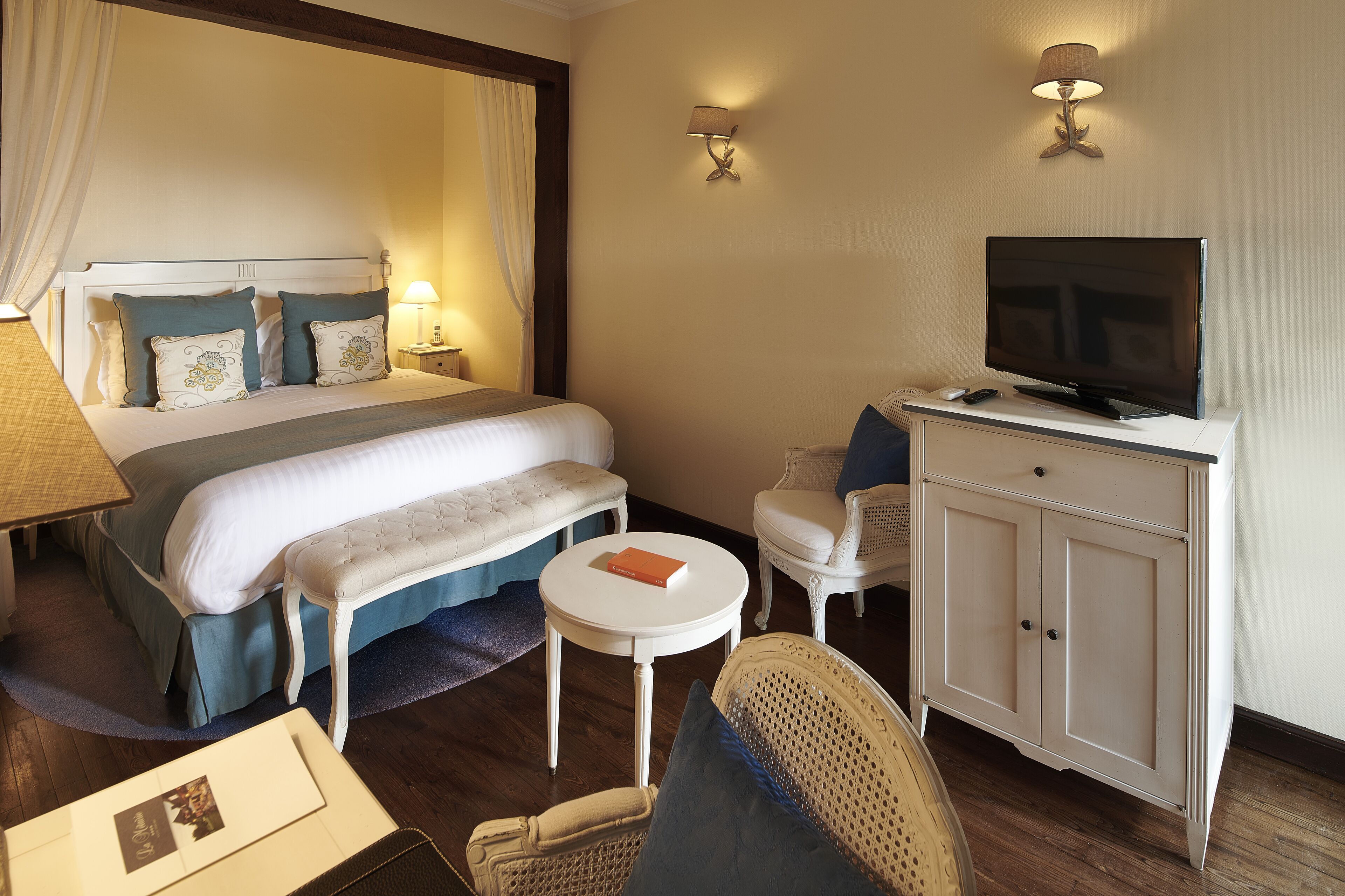 Une chambre d’hôtel avec un lit, un téléviseur posé sur un meuble, une petite table ronde, une chaise et un bureau.