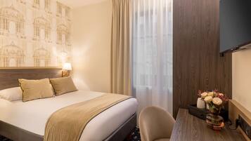 Een hotelkamer met een groot bed, een bureau met een bloemenvaas en een muur met een gedessineerd muurschildering.