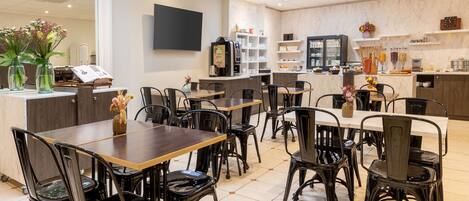 A modern cafe with multiple tables and chairs, a coffee machine, and shelves with various items.