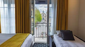 Une chambre d’hôtel avec deux lits, un balcon et une vue sur un immeuble doté d’une tour.