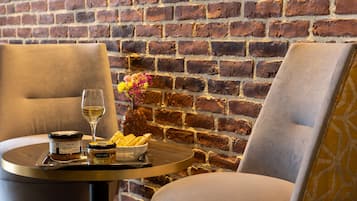 A dining area with two chairs, a table with a glass of wine, jars of jam, and a bowl of chips.