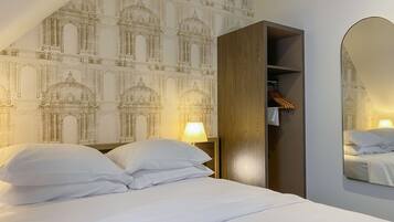 A bedroom with a bed, a nightstand, a mirror, and a wardrobe.
