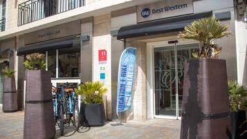 Een hotelingang met een bord voor Best Western, een banner voor fietsverhuur en een bord van Royal Hotel Caen.