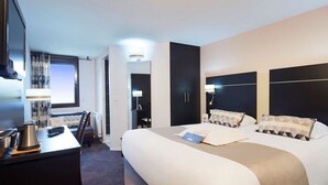 Een hotelkamer met een groot bed, een bureau met lamp, een televisie en een kledingkast.