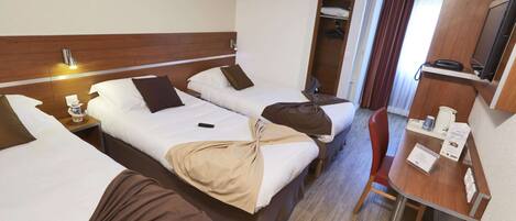 A hotel room with two beds, a desk, a chair, a TV, and a wardrobe.