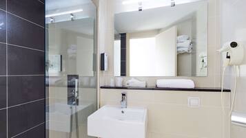 A modern bathroom with a glass shower enclosure, a white sink, and a mirror above it.
