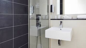 A modern bathroom with a glass-enclosed shower, a white sink, and a mirror above it.