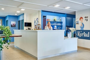 A reception desk with a blue and white color scheme, a television, and a plant.
