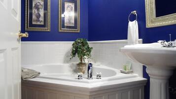 A bathroom with a bathtub, a sink, and two framed pictures on the wall.