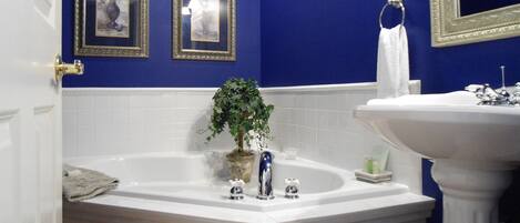 A bathroom with a bathtub, a sink, and two framed pictures on the wall.
