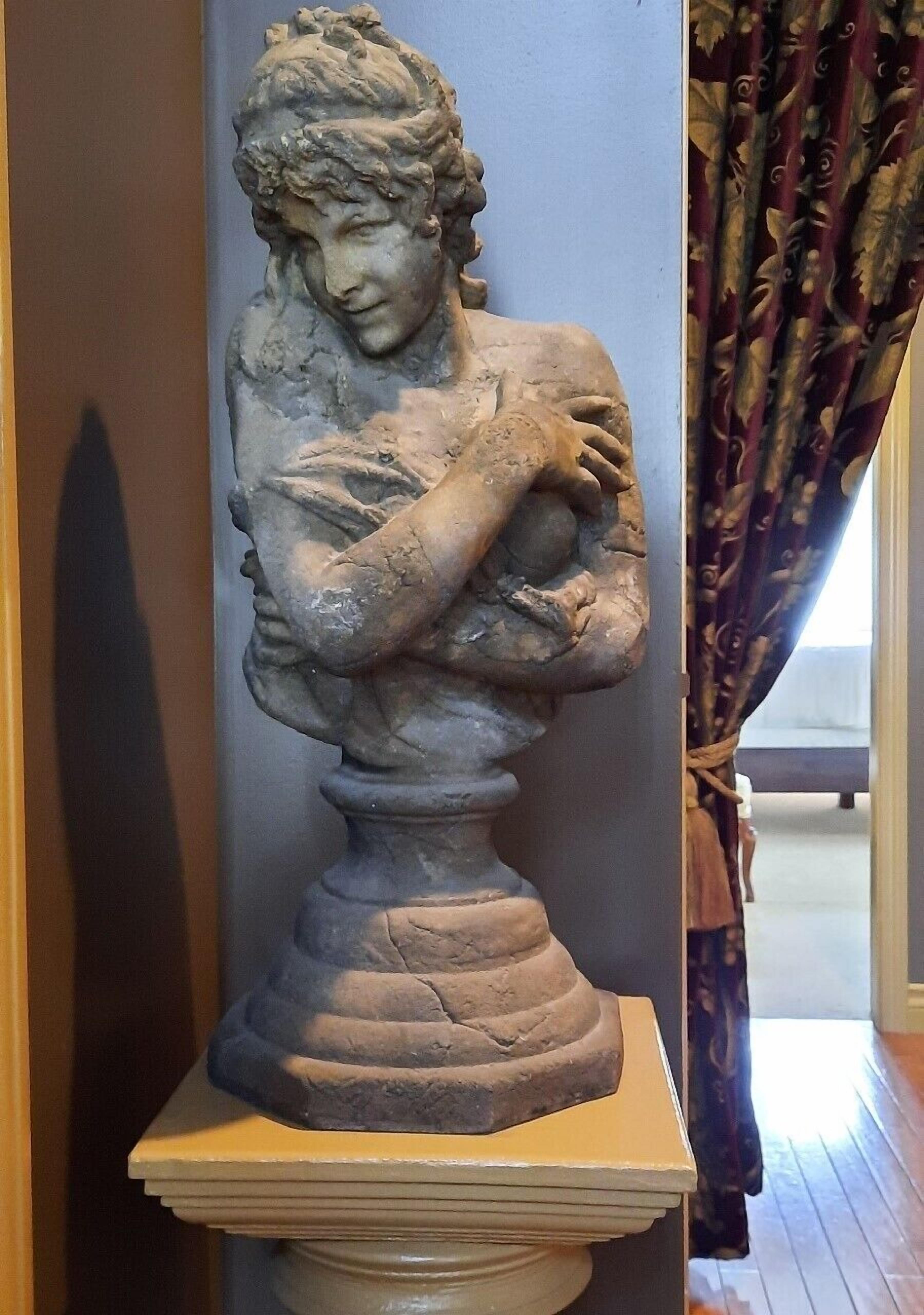 A sculpture on a pedestal in a room with a patterned curtain and a wooden floor.