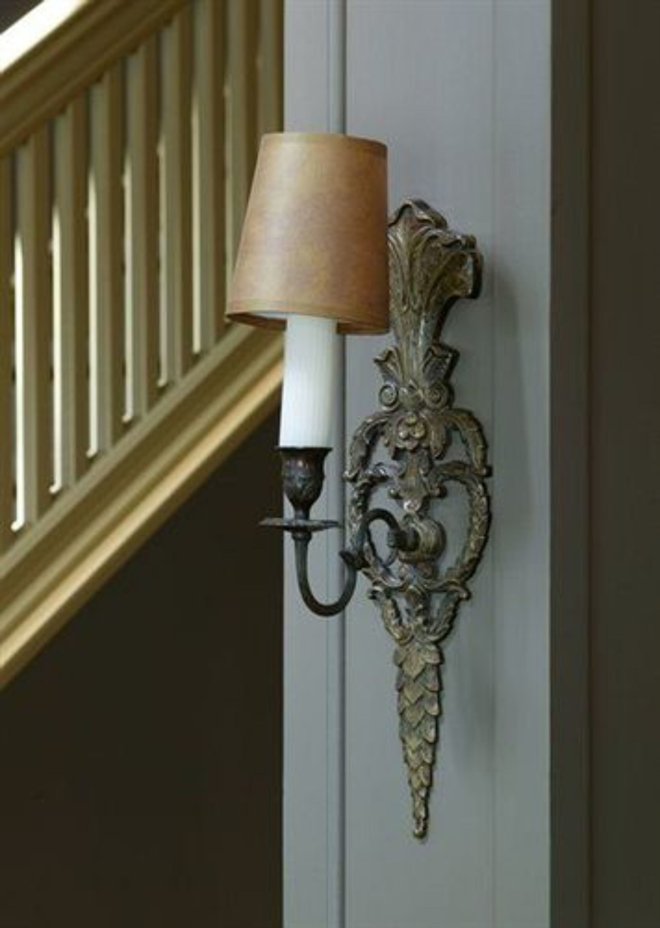 A wall-mounted lamp with a decorative metal design and a white shade.