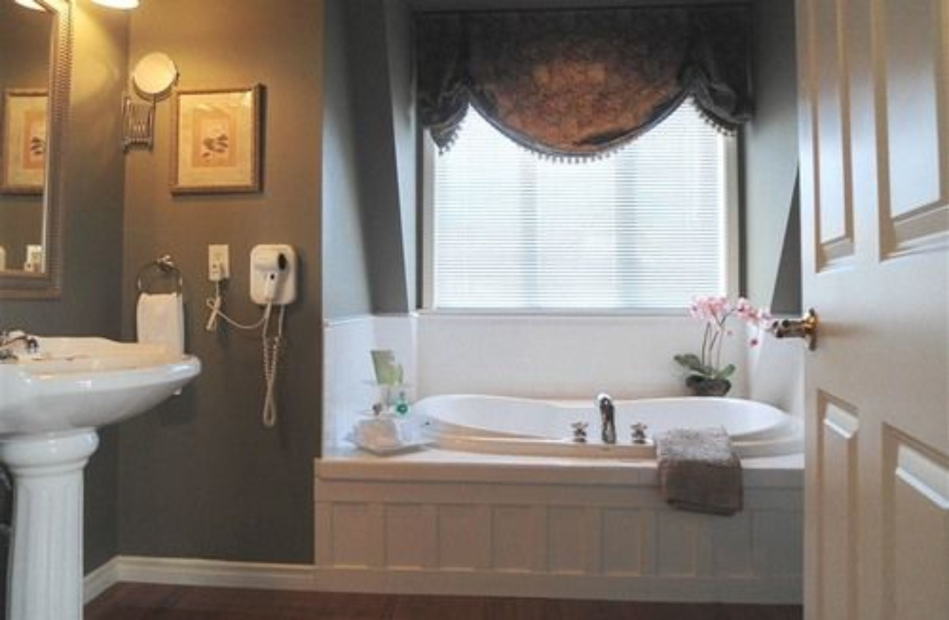 A bathroom with a bathtub, a sink, and a window with a curtain.