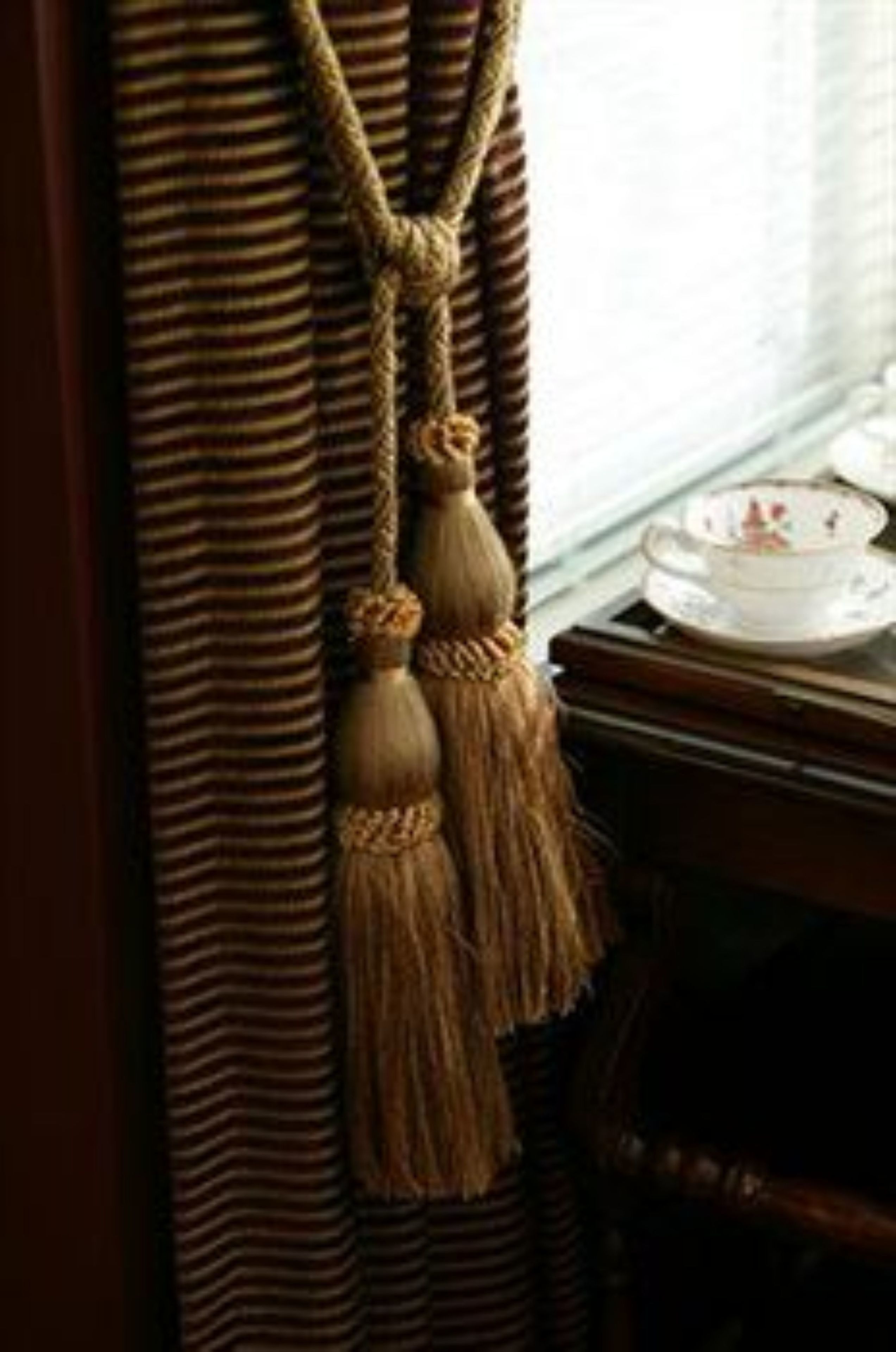 Un rideau à rayures, orné d’une frange pendant.