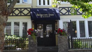 The exterior of Beacon Inn at Sidney, featuring a stone entrance, a black awning with the inn's name, and a brick wall with flower boxes. - Beacon Inn at Sidney (Sidney)