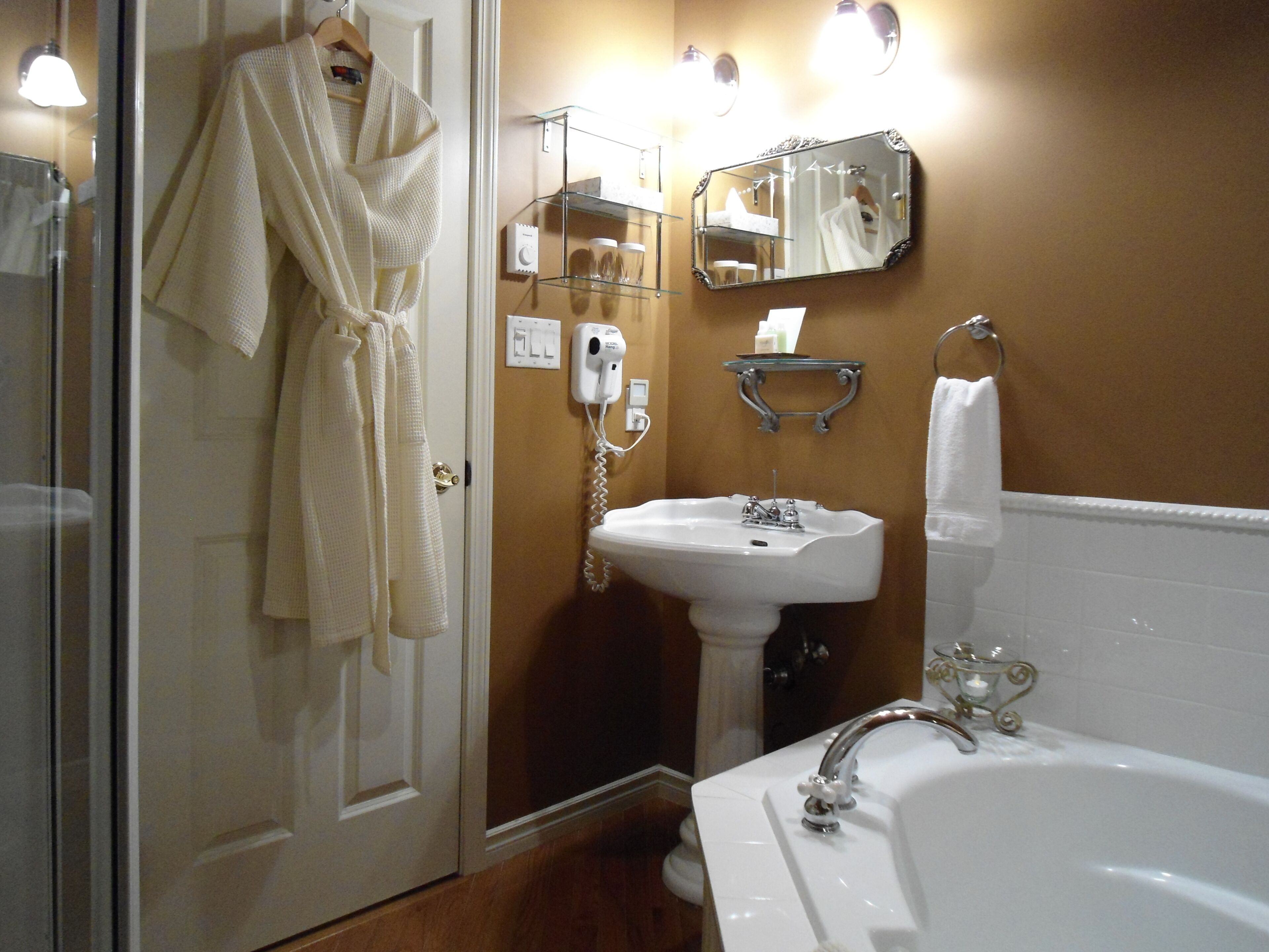 A bathroom with a sink, mirror, and robe hanging on the door.