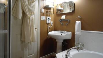 A bathroom with a sink, mirror, and robe hanging on the door.