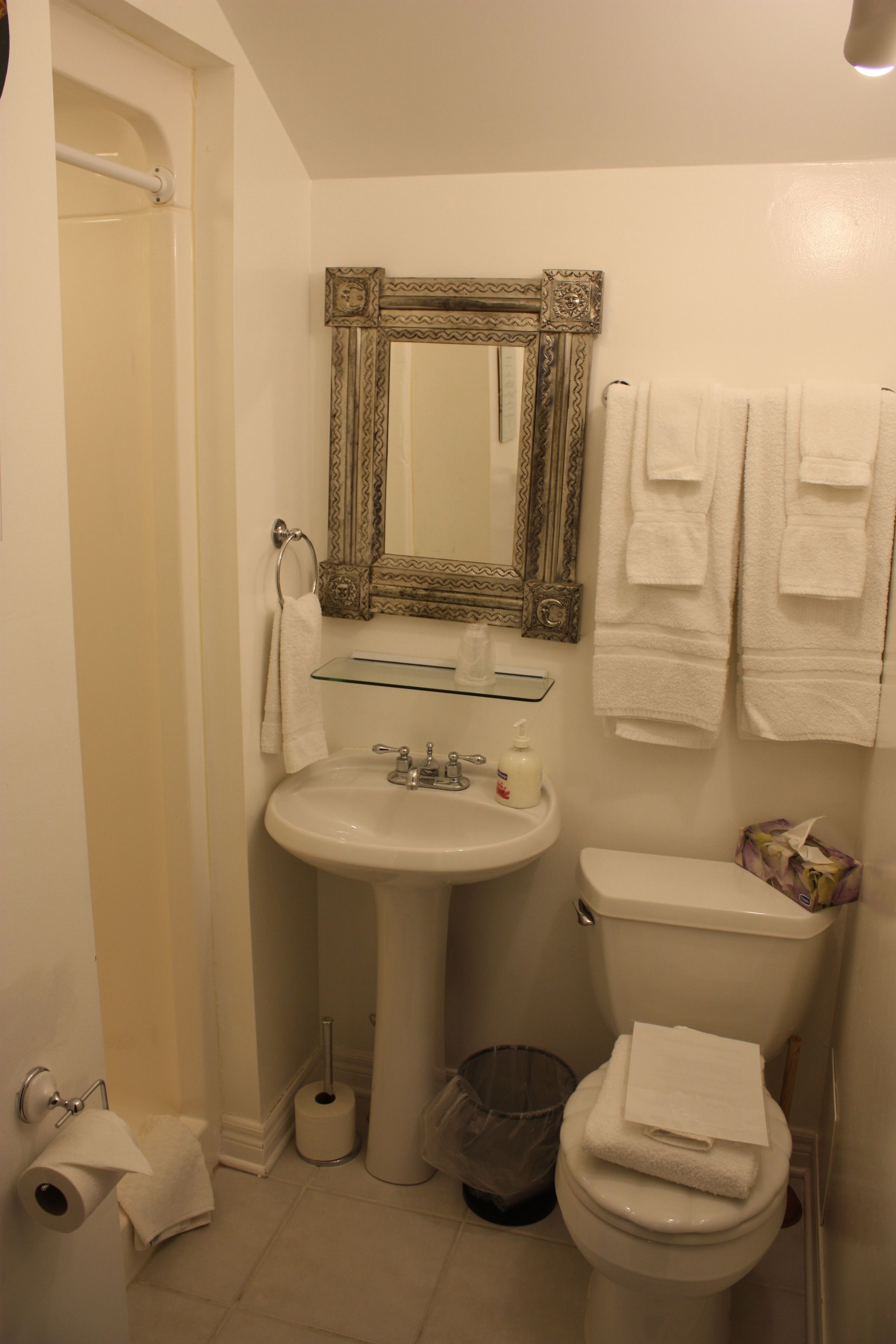 A bathroom with a sink, toilet, and a mirror with a decorative frame.