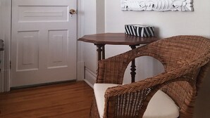 A room with a white door, a mirror, a wicker chair, and a small table. - Ellis House B&B, Niagara Falls (Niagara Falls)