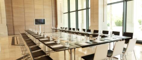 A conference room with a long table, chairs, and a television screen.