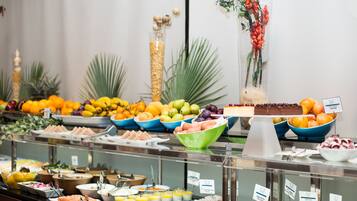 A buffet with various food items and a decorative plant arrangement.