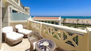 A balcony with wicker furniture, a glass table, and a view of the beach and ocean. - Hotel Las Arenas Balneario Resort (Valencia)