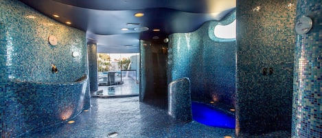 Una habitación con paredes y suelo de mosaico, una bañera y zona de ducha.