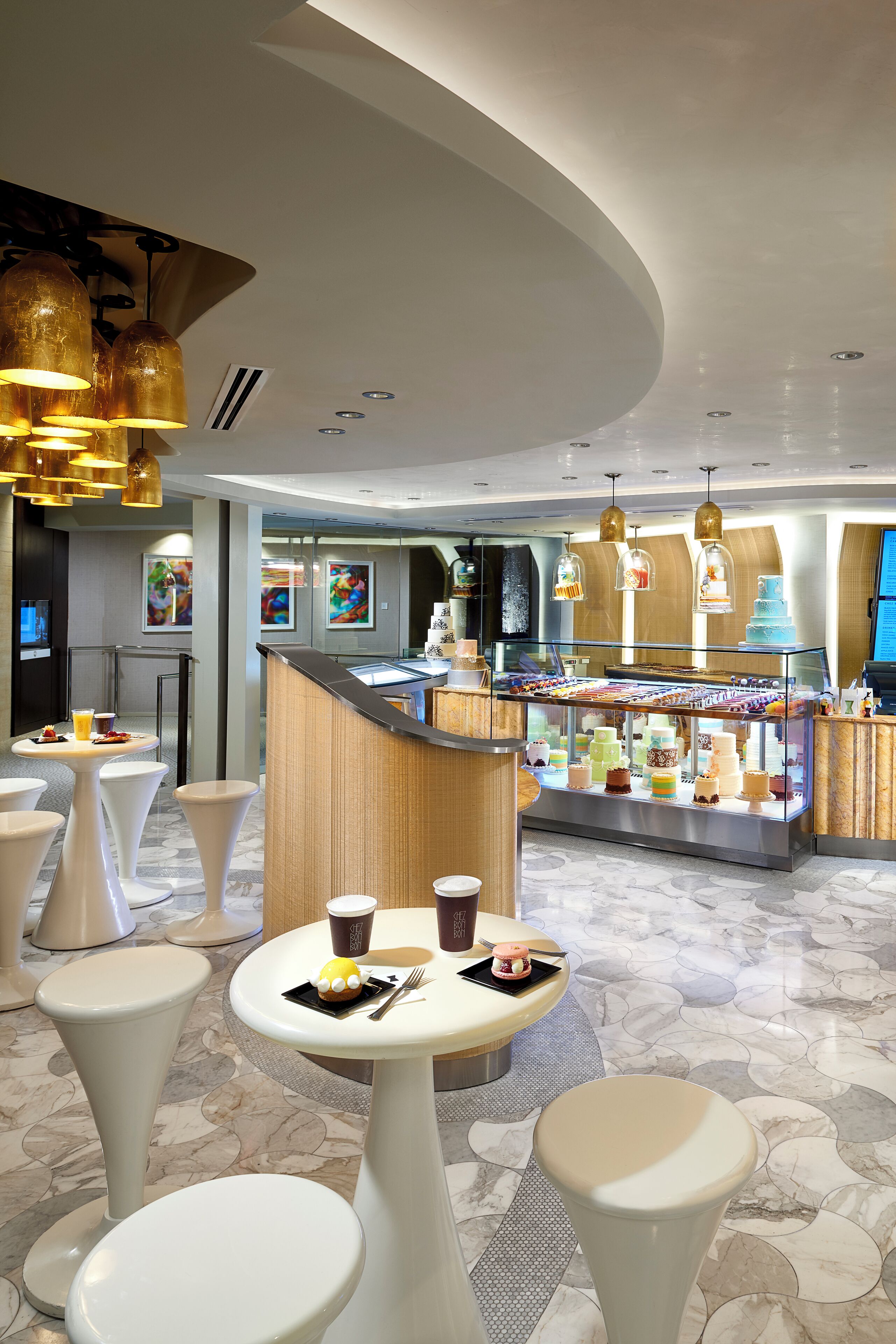 Een moderne hotellobby met ronde tafels, een dessertbuffet en een zithoek.
