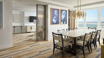 A dining area with a large table and chairs, a chandelier, and artwork on the walls.