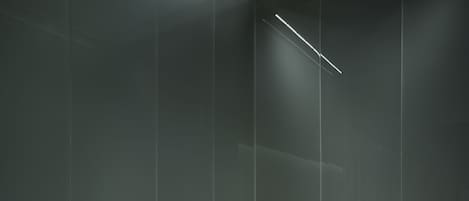 A modern bathroom with a minimalist design, featuring a glass shower enclosure and two white marble sinks.