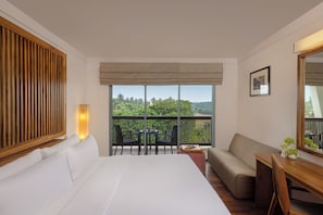 A hotel room with a bed, a sofa, a small table, and a balcony with a view of trees. - The Eden Beruwala (Beruwala)