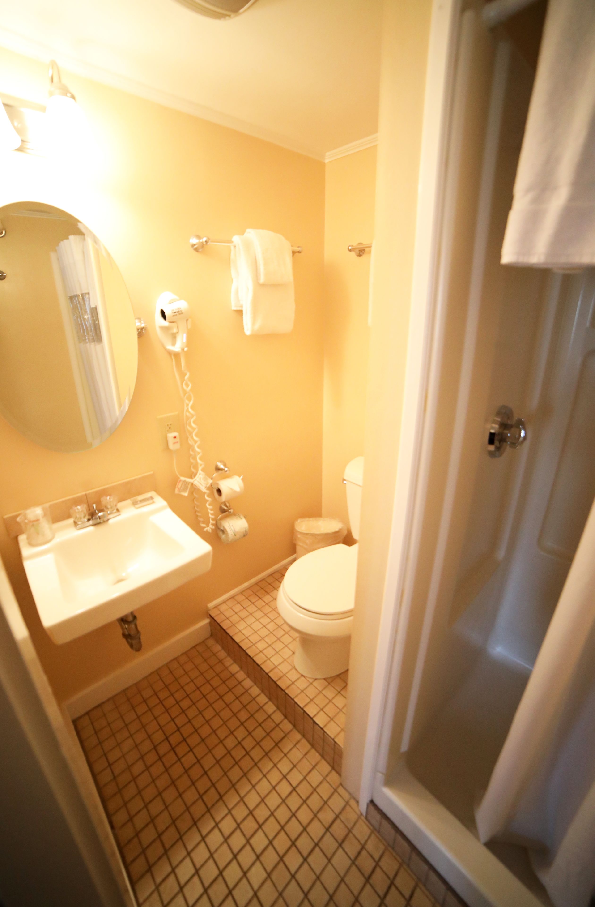 A compact bathroom with a sink, toilet, and a shower area.