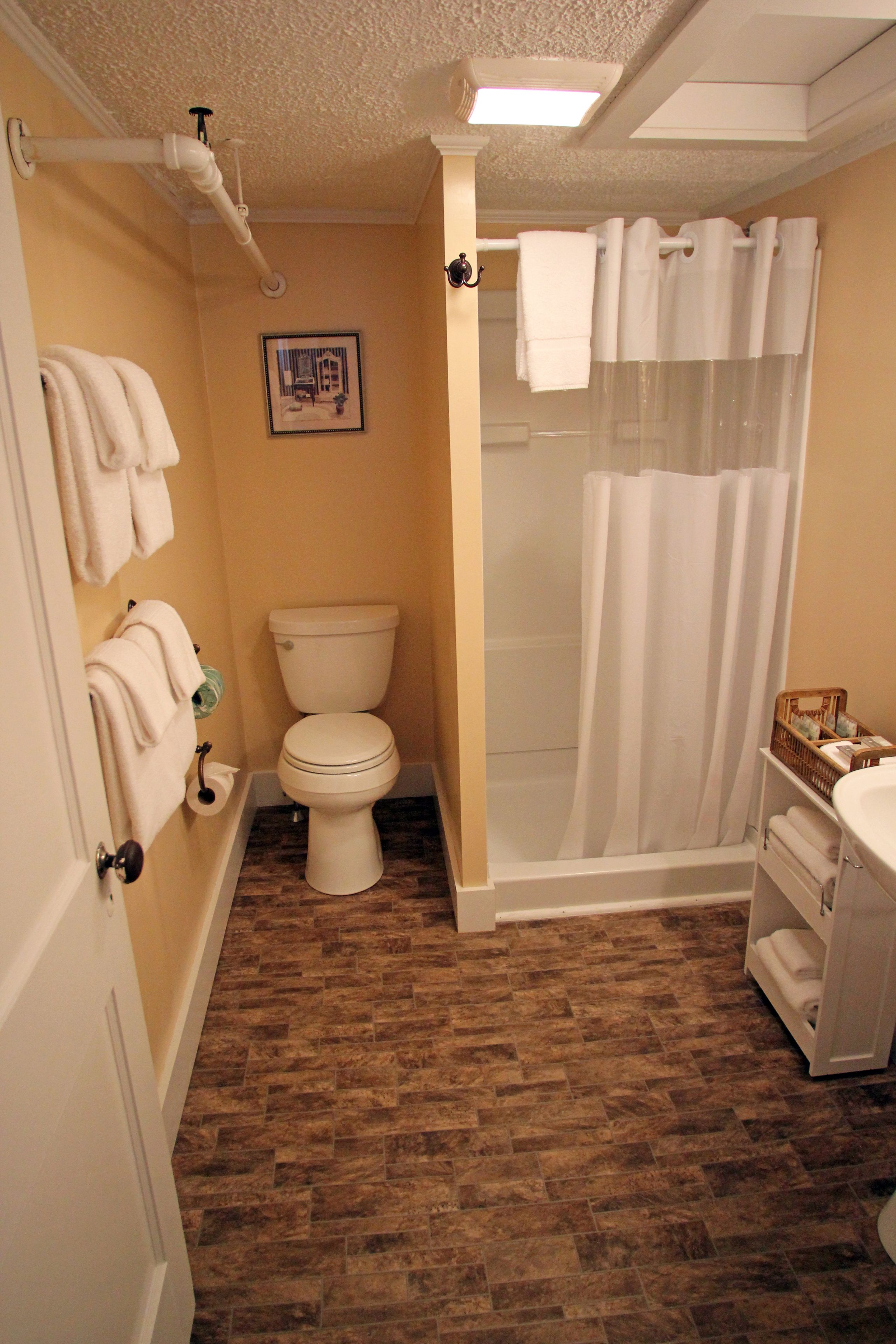 A bathroom with a toilet, shower, and sink.