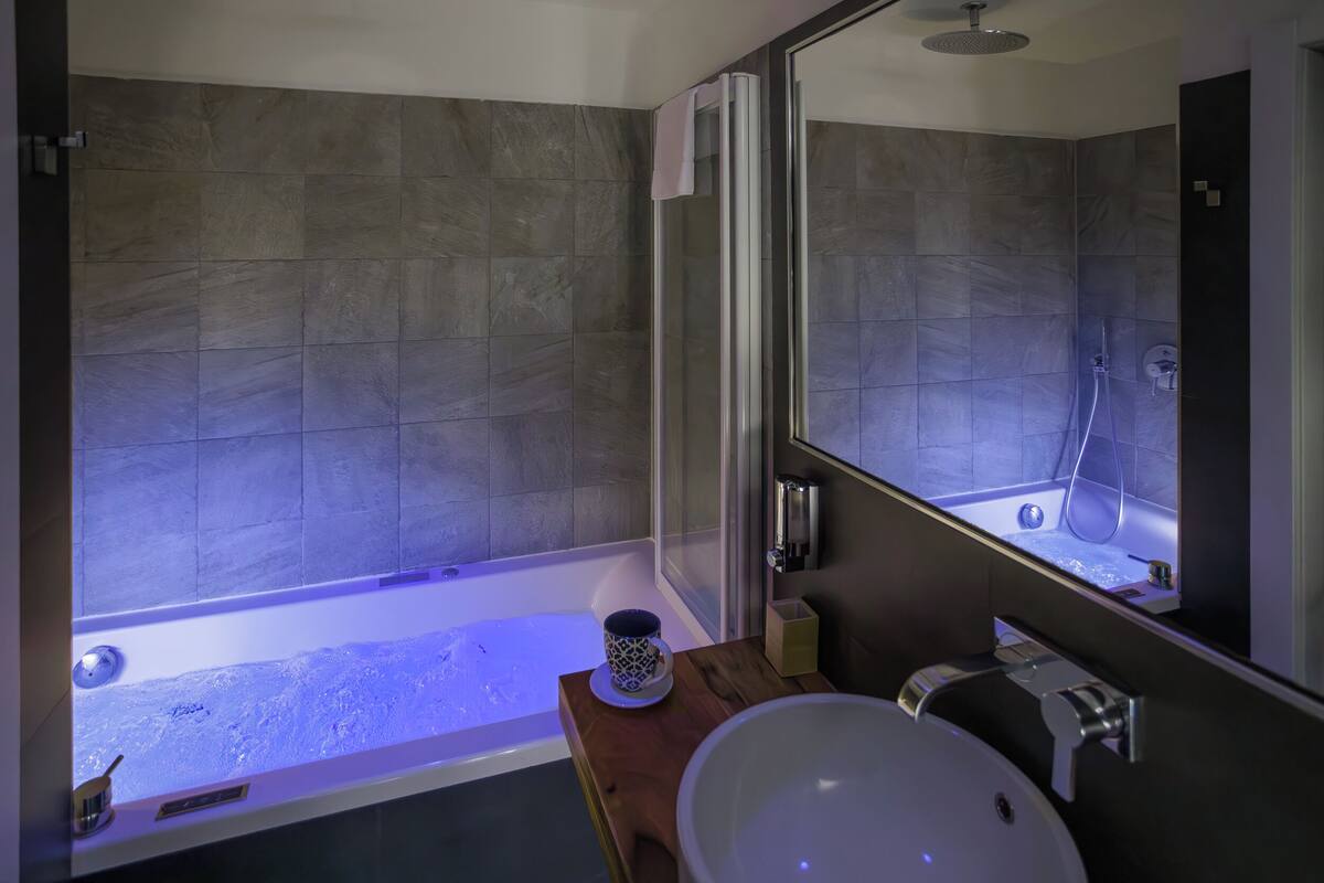 A modern bathroom with a bathtub, a large mirror, and a wooden vanity.