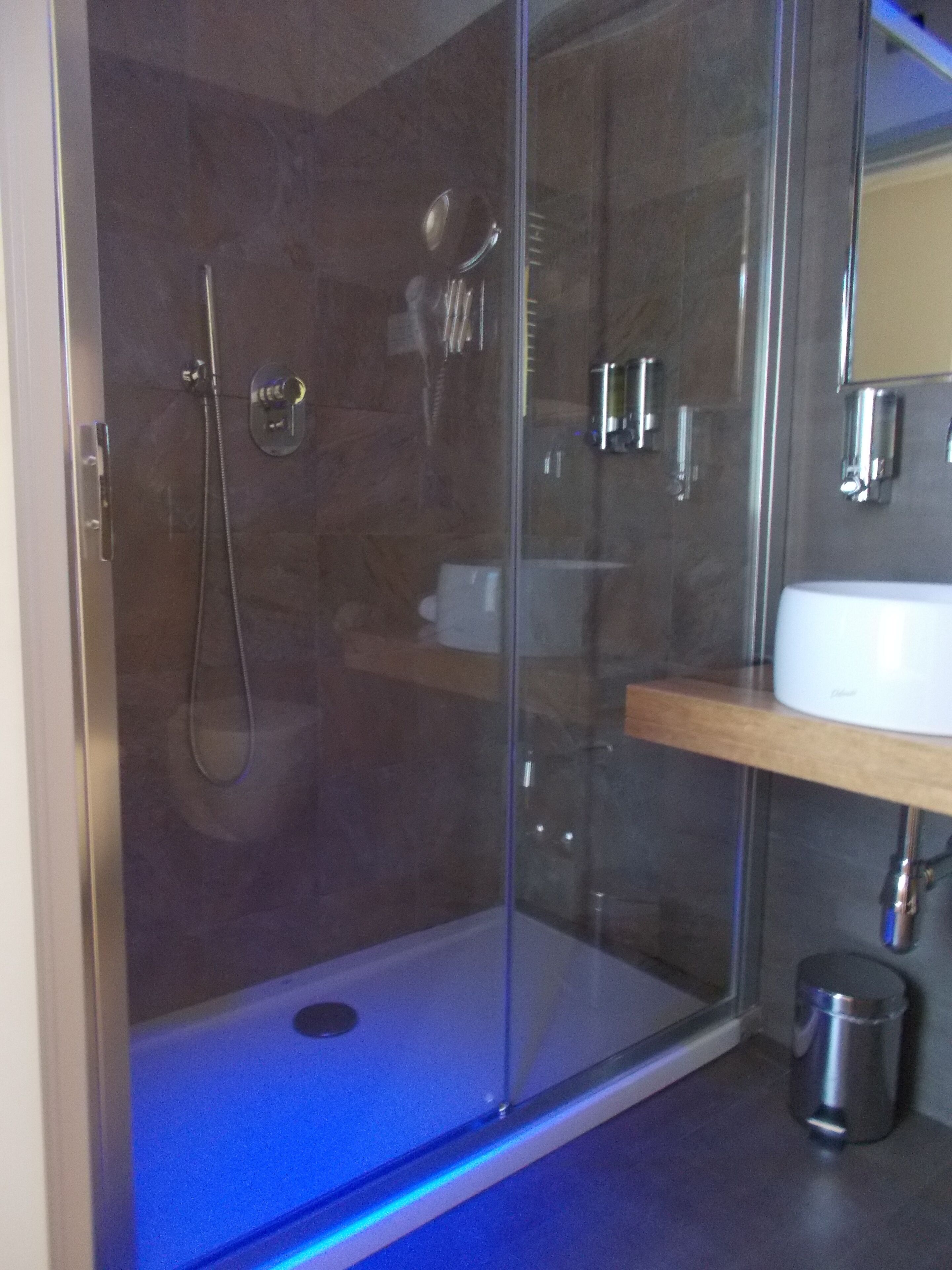 Een douche met glazen wand, een handdouche en een wandmengkraan.
