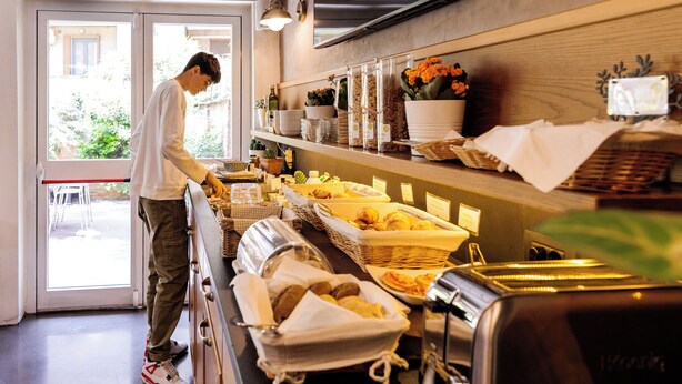 Un buffet de petit-déjeuner proposant une variété d’aliments, avec une personne chargée de servir.