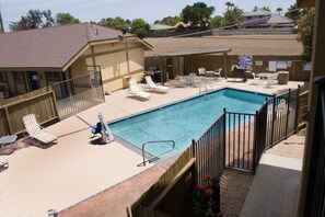 A backyard with a swimming pool, lounge chairs, and a barbecue area.