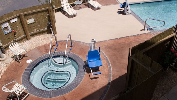 Una piscina en la azotea con hidromasaje, sillas de descanso y una valla de madera.