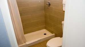 Un baño pequeño con ducha, inodoro y perchero para toallas.