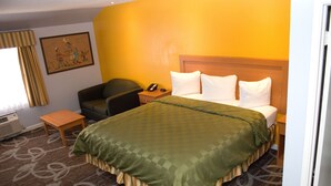 Una habitación de hotel con cama, escritorio, silla, mesita de noche, teléfono y un cuadro en la pared.