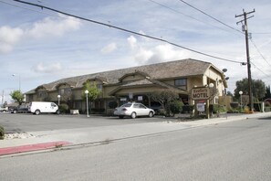 A motel with a two-story structure, a parking lot, and a street view.