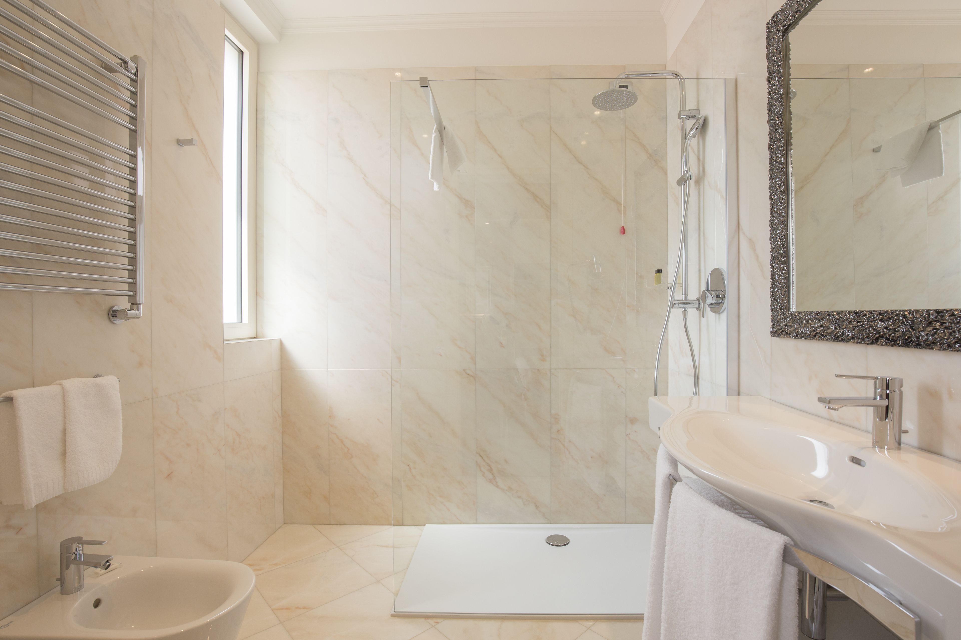 Un bagno moderno dotato di doccia, lavandino e specchio.