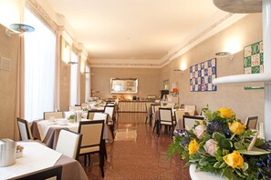 A hotel dining area with multiple tables, chairs, and a buffet setup. - Hotel San Pietro (Verona)