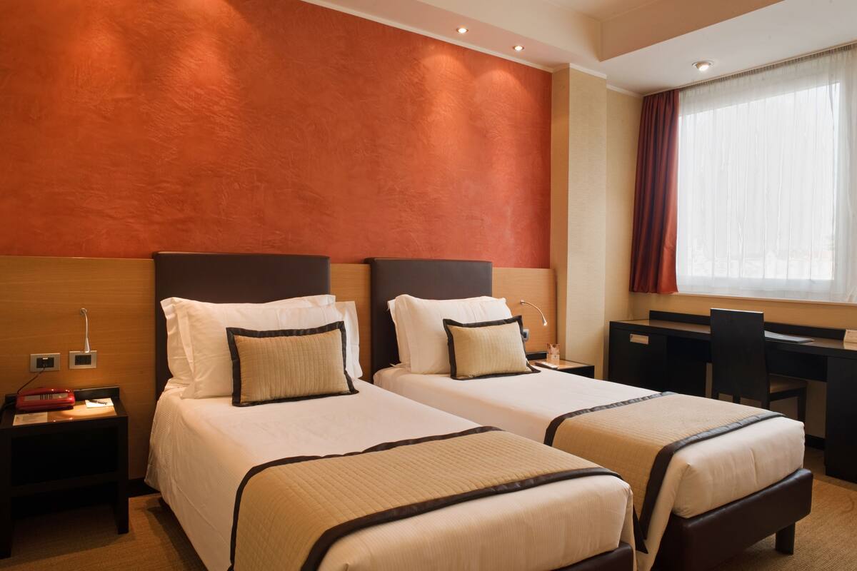 Ein Hotelzimmer mit zwei Betten, einem Schreibtisch und einem Sessel.