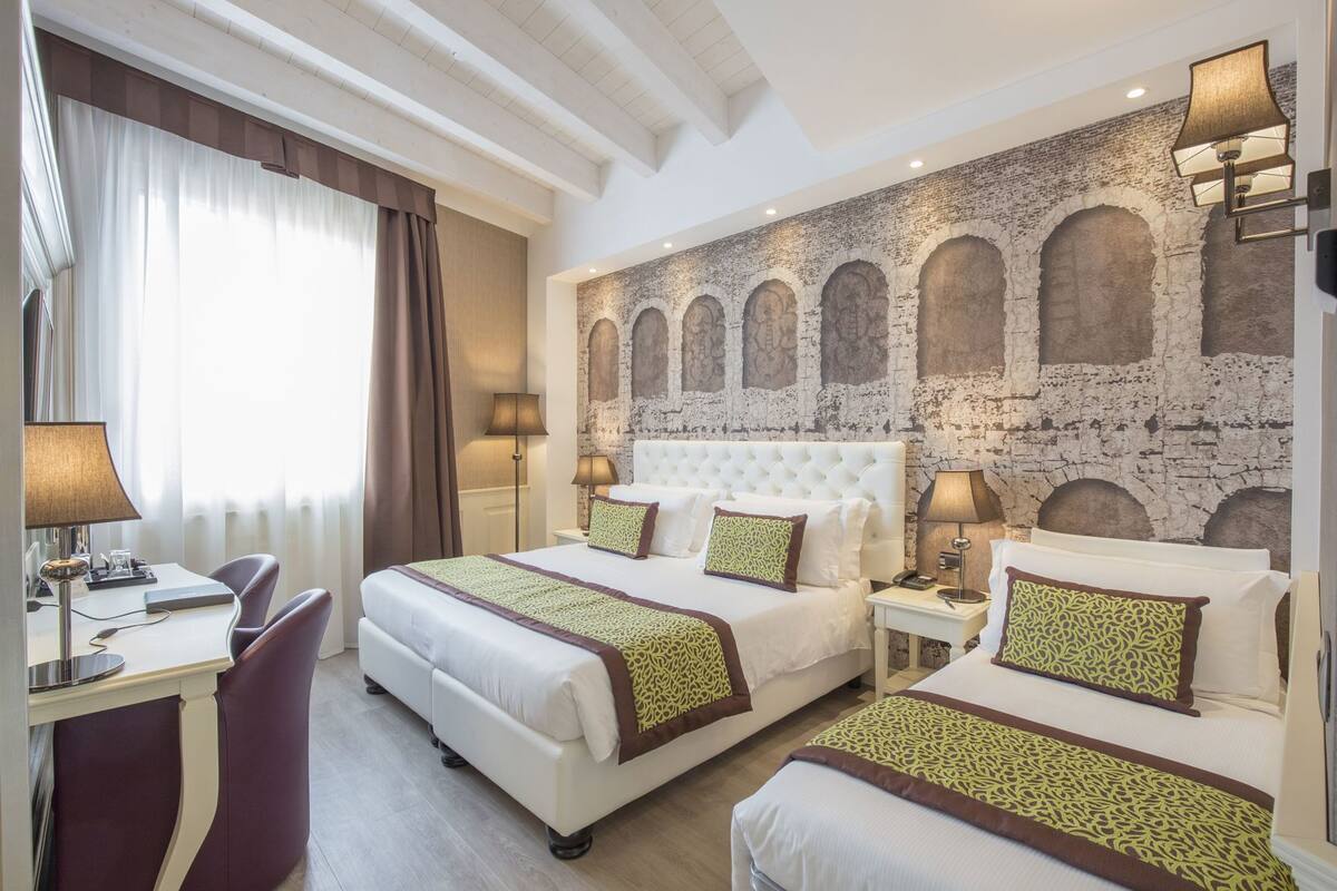 Ein Hotelzimmer mit zwei Betten, einem Schreibtisch und einer großen Bogenwand.