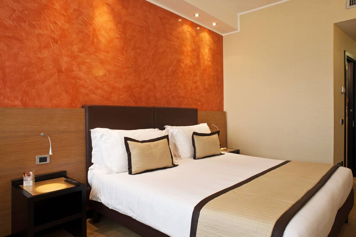 Ein Hotelzimmer mit einem großen Bett, einem Holz-Kopfbrett und einem Nachttisch mit Lampe.