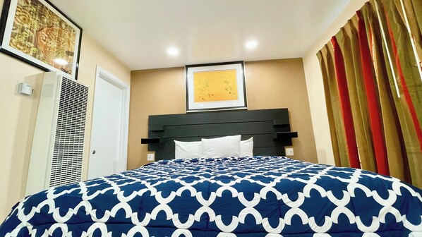 A neatly made bed with a patterned bedspread, a headboard, and a framed picture on the wall. - Ocean Inn (San Francisco)