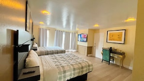 A hotel room with two beds, a TV, a desk, and a window with curtains. - Ocean Inn (San Francisco)