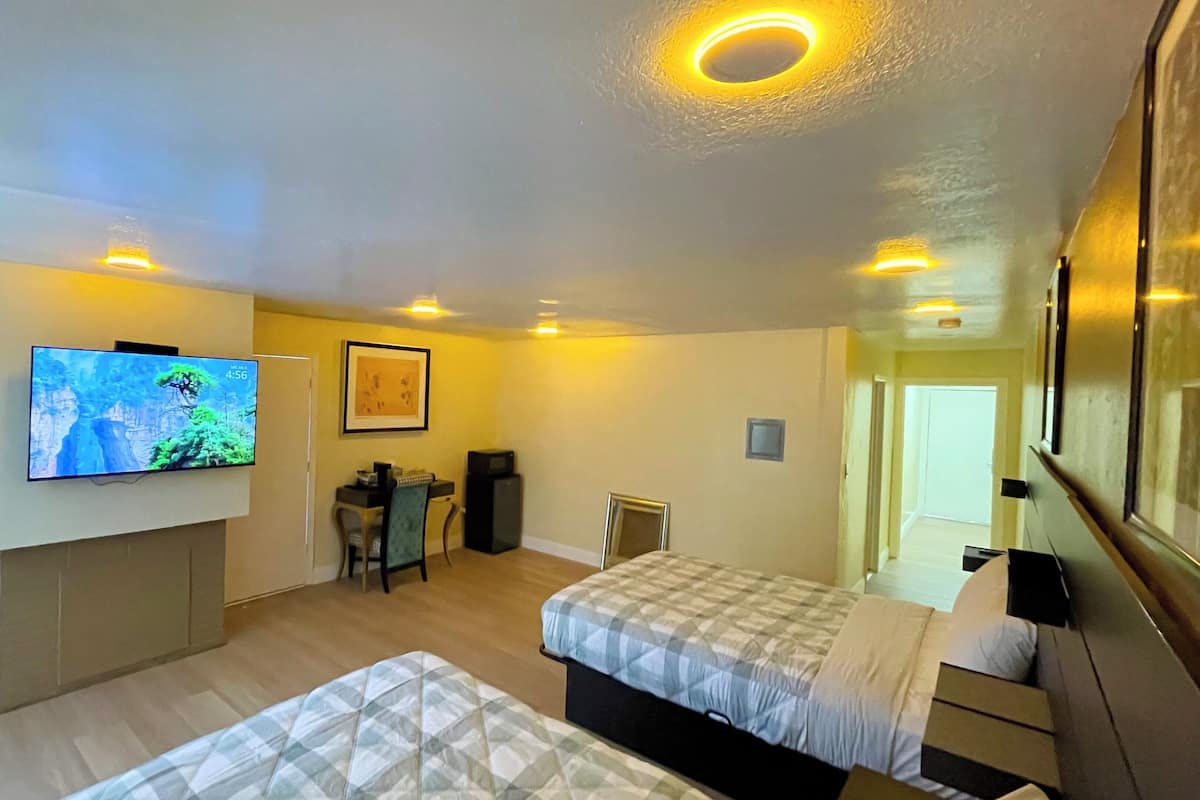 A hotel room with a bed, a desk with a chair, a television mounted on the wall, and a small table with a chair.